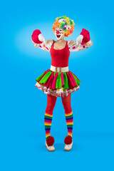 Funny female clown pointing down at blank template copy spase for advertising, posters, greetings, invitations. Entertainer as Joker in a suit and wig, with clown whiteface makeup