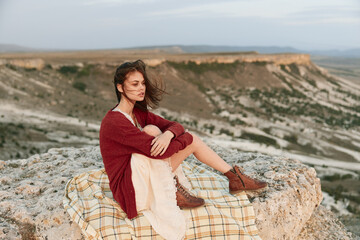 Woman in red sweater sitting on mountain cliff edge with brown boots adventure and nature beauty concept