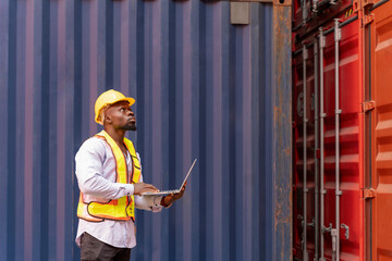 african man in safety gear and hardhat using laptop computer at container cargo,foreman checking electronic seal on container box,worker working in shipping yard