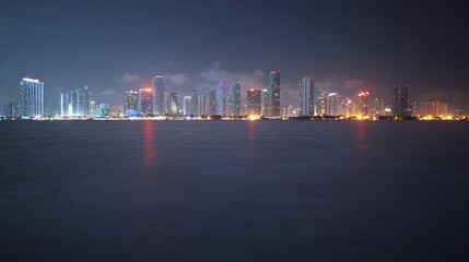 Fototapeta premium A nighttime cityscape featuring illuminated skyscrapers along a waterfront.