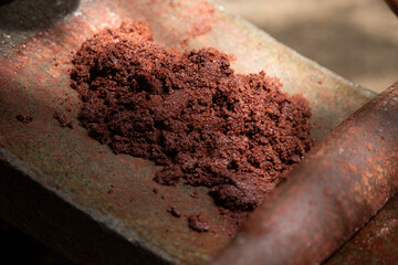 A woman in Oaxaca Mexico manually producing organic chocolate on a metate, an ancient stone tool for grinding food products.