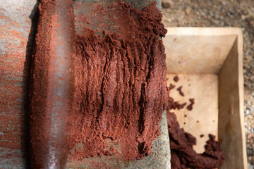 A woman in Oaxaca Mexico manually producing organic chocolate on a metate, an ancient stone tool for grinding food products.