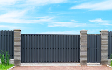 Modern aluminium sliding gate. Gate portal of suburb door house. Modern steel fence around the...
