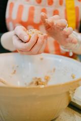 A woman is making a cake in a bowl. She is holding the bowl in her hands and has a spoon in her other hand