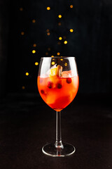 Special winter edition spritz coctail with orange and cranberries on dark background. Festives vibes, place for text.