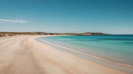 Obraz premium Beautiful empty beach with vivid turquoise waters meeting a soft sandy shoreline under a bright, cloudless sky.
