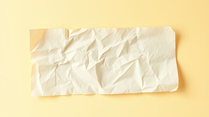 Obraz premium Cream-colored crumpled paper sheet on a pale yellow background, ideal for design mockups and texture overlays.