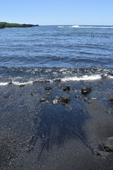 The black sand lava and magma beaches with the turquoise pacific ocean in the back on the big island of Hawaii
