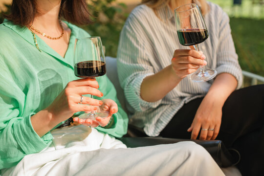 Close-up of two women sitting on a terrace drinking red wine in summer