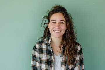 Fototapeta premium Portrait of a smiling woman in her 30s wearing a comfy flannel shirt over pastel green background