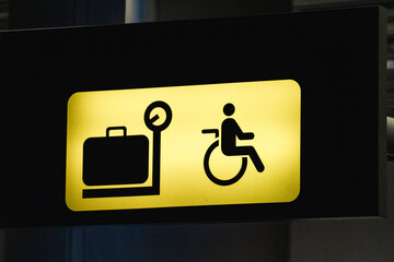 Yellow baggage claim sign with a luggage and wheelchair user symbol