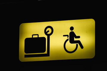 Yellow baggage claim sign with a luggage and wheelchair user symbol