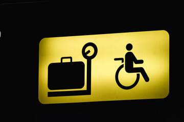 Yellow baggage claim sign with a luggage and wheelchair user symbol
