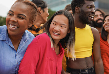 Obraz premium Crowd of multiracial people having fun hugging each other in the city - Diverse young friends and party concept - Focus on asian woman face