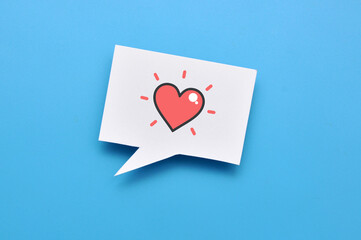 A red paper heart on a speech balloon. A symbol of love, conversation and declaration of love