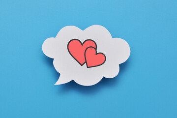 A red paper heart on a speech balloon. A symbol of love, conversation and declaration of love