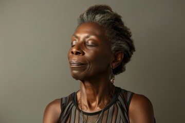 Obraz premium Portrait of a satisfied afro-american woman in her 50s dressed in a breathable mesh vest in pastel gray background