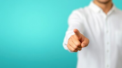 A person in a white shirt points towards the viewer against a solid teal background, conveying focus and engagement.