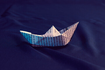 Obraz premium Origami Paper Boat On Navy Blue Fabric Background