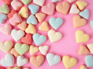 Fototapeta premium Colorful sugar hearts arranged on a pink background, creating a vibrant and sweet backdrop for Valentine's Day or love-themed content, copy space