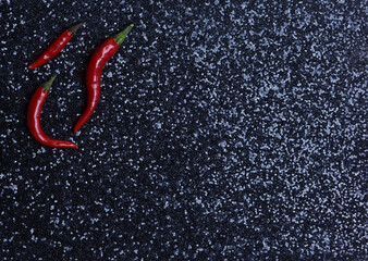 Red hot chili peppers on black glitter background. Top view. Copy space.