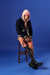 Naklejka premium Young man with a prosthetic leg showcases his unique style while sitting on a stool.