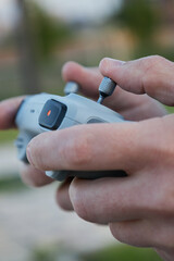 Male hands hold a drone control panel, close up. Management by quadcopter flight and videotaping from above. Day time outdoor. Videography work, hobby, closeup