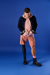 Young man showcases a prosthetic leg while wearing a trendy outfit in a bright setting.