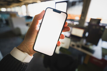 Hand holding smartphone empty screen mockup office interior