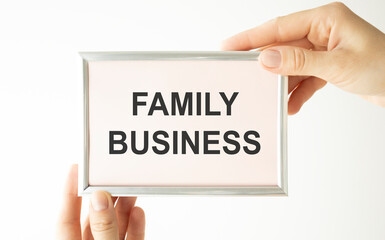 Closeup on businessman holding a card with text FAMILY BUSINESS, business concept image with soft focus background