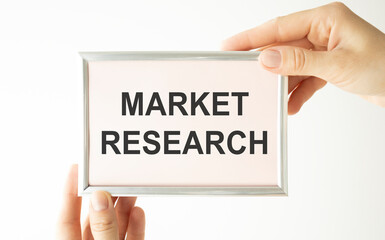 Woman hands holding cardboard card with words Market Research.
