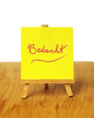 A yellow thank you note with the word 'Bedankt,' meaning 'thank you' in Dutch, on a miniature easel.