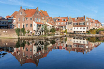 De Bocht (The Bend), a famous corner in the historic town of Enkhuizen, reflecting in the water beneath a clear blue sky.