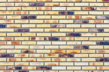 Brick wall with yellow multicolored bricks, textured background.