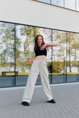 Obraz premium A dancer showcases her skills outdoors near a reflective building on a sunny day, expressing movement with grace and energy