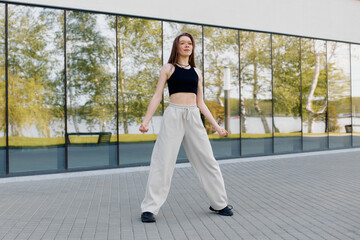 Fototapeta premium A young woman performs an energetic dance move on a paved area