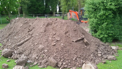 Erdhügel, Bodenaushub mit Betonplatten und Minibagger im Hintergrund. In einem Garten in Lippetal Büninghausen, Nordrhein-Westfalen.