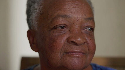 Close-up face of a pensive black senior woman. Contemplative African American elderly person with thoughtful emotion
