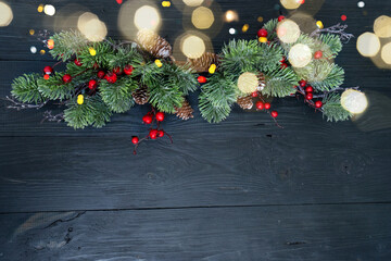 Beautiful holiday decoration featuring evergreen branches, berries, and pine cones on a rustic wood background.