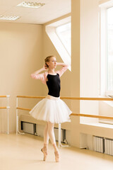 Ballerina strikes delicate pose with arms raised