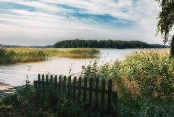 Beautiful, deserted beach and jetty in Poland in midsummer. Lonely idyll without people in the great outdoors. Wooden pier on the beach and pier for boats. Fantastic nature in deserted paradiese.