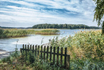 Obraz premium Beautiful, deserted beach and jetty in Poland in midsummer. Lonely idyll without people in the great outdoors. Wooden pier on the beach and pier for boats. Fantastic nature in deserted paradiese.