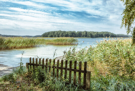 Beautiful, deserted beach and jetty in Poland in midsummer. Lonely idyll without people in the great outdoors. Wooden pier on the beach and pier for boats. Fantastic nature in deserted paradiese.