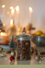 Various Christmas decorations, cookies, chocolate, nuts and tangerines, wine glasses and lit candles on the table. Holiday hygge at home. Selective focus.