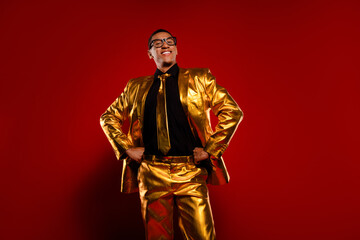 Glossy golden suit with stylish young man against vibrant red background, embodying modern elegance...