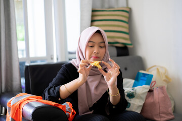 A young Indonesian woman wearing a hijab is seen really enjoying her sandwich.