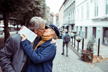 Romantic senior couple kissing on a city street during vacation