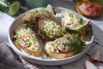 A plate with sandwiches with cottage cheese, radish and cucumber in rustic style