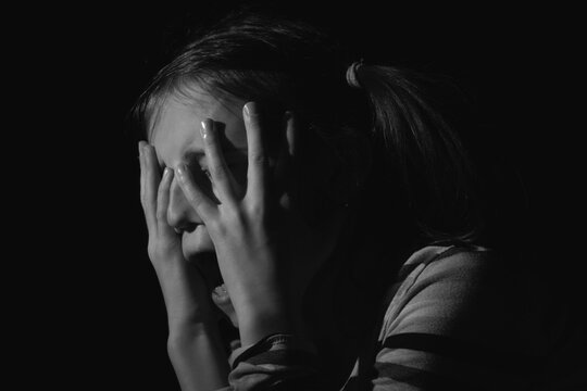 Stressed, unhappy young adolescent girl crying and feeling exhausted or depressed alone. Horizontal black and white image.