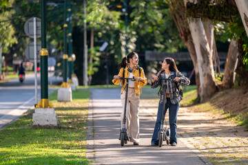 Two women riding scooters on a sidewalk